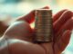 Hand holding coins, financial growth concept.
