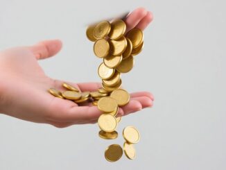 Person reaching for falling golden coins.